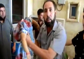 A man  holds the lifeless body of his decapitated daughter, executed by ISIS
